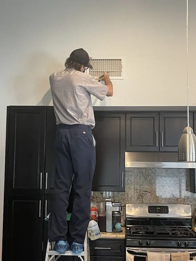 Technician inspecting an air vent during HVAC service in Moorpark